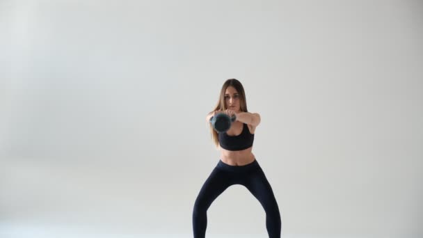 Athletic woman doing kettlebell swings. Photo of latin woman with good physique in fashionable sportswear isolated on — Stock Video