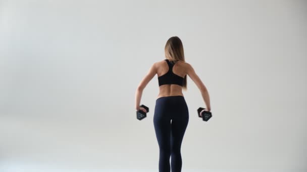 Jonge vrouw bodybuilder doen oefening met halters. Foto van sportieve vrouw in training oppompen spieren van de rug — Stockvideo