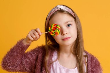 Küçük kız okul tatilinde lolipoplardan hoşlanır. Küçük mutlu okul çocuğu lolipop yiyor. Çubuklarda büyük girdap lolipoplar