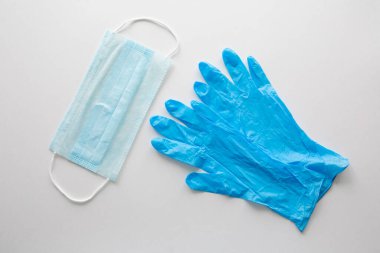 Tıbbi eldivenler ve beyaz bir arka planda cerrahi maske. Salgın Covid-19, koronavirüs koruması..