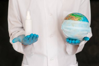 Konsept, gezegeni koronavirüsten korumak. Antiseptiği küreye dök. Covid-19 ve dünya doktorun elinde.