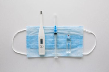 Siyah arka planda tıbbi maske. Yüz maskesi. Hastalıklar için maske. Termometre ve ilaç. Tek bir kişinin görüntüsü. Yüzünde tıbbi solunum bandajı var. Karantina koronavirüsü konsepti