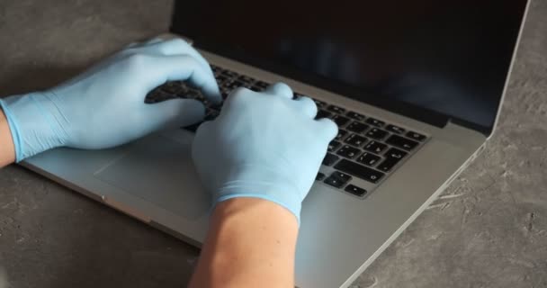 Joven hombre de negocios lleva guantes de mascarilla médica trabajando en el ordenador portátil sentado en el escritorio de la oficina en casa. Autónomo — Vídeos de Stock