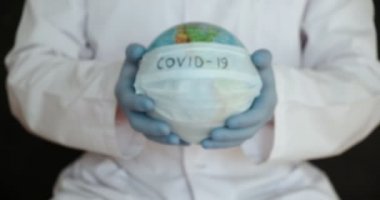 Mavi arka planda izole edilmiş tıbbi elbise, steril yüz maskesi eldivenli erkek doktor görüntüsü. Salgın hastalıklar.