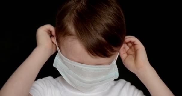 Närbild av en pojke med mask. baby i medicinsk mask ler. — Stockvideo