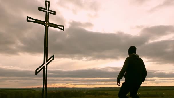 Silueta muže na vrcholu hory, hledí s nadějí na křesťanské kříže. Člověk přiznání na kříž, na pozadí západ slunce.