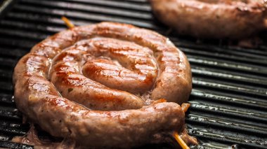 Elektrikli barbekü ızgarasında kızarmış sarmal sosis. Yemek pişirmek için elektrikli ızgara. Alman Bratwurst domuz sosisi.