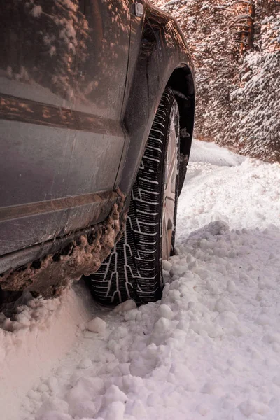 Car tires on winter road covered with snow. Vehicle on snowy alley in the morning at snowfall.