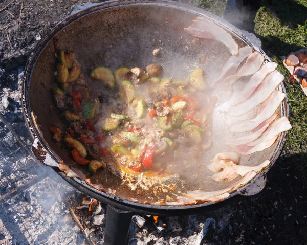 Fried eggs with bacon and vegetables on a bonfire. the cooking p — 스톡 사진