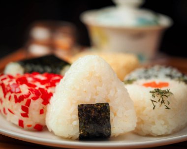 Çay seremonisi ve farklı el yapımı onigiri yakın çekim. Su ısıtıcısı ve kupalı geleneksel Japon yemekleri..