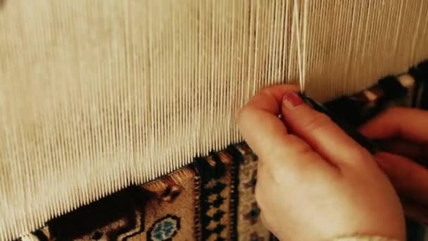 Carpet weaving. Turkish woman weaving a carpet with peace of genuine camel wool with a manual waving machine. — Stock Video