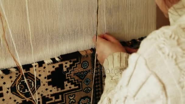 Carpet weaving. Turkish woman weaving a carpet with peace of genuine camel wool with a manual waving machine. — Stock Video