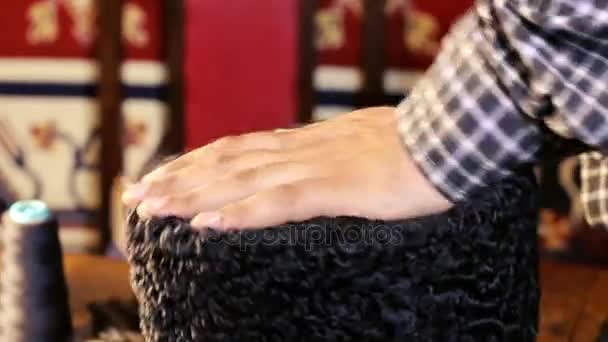 Hoed-maker werkt. Hoed besluitvormingsproces. Astrachan hoed van originele wol en leer. Astrachan hoed en vilt mantel. Hoed maker schaar concept op houten textuur. — Stockvideo