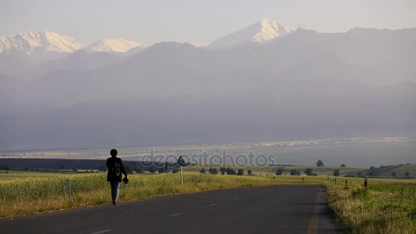 A man walking along a road in front of nature in summer — Stock Video