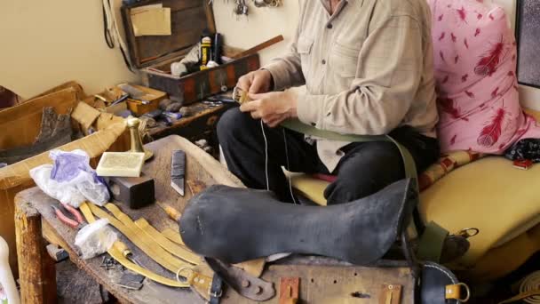 Saddler. Saddle manufacture. Leather goods craftsman at work in his workshop. Artisan Leather. Saddle crafting. Old vintage art. Traditional sewing leather to the point of saddle. Azerbaijan old art. — Stock Video