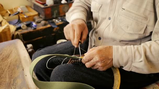 Saddler. Fabricação de selas. Artesanato de artigos de couro no trabalho em sua oficina. Couro artesanal. Artesanato em sela. Arte vintage antiga. Couro de costura tradicional ao ponto de sela. Azerbaijão arte antiga . — Vídeo de Stock