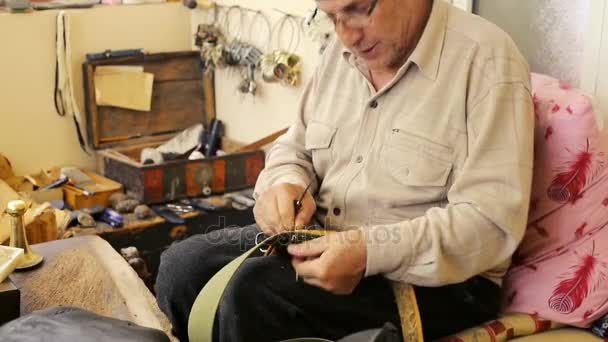 Saddler. Saddle manufacture. Leather goods craftsman at work in his workshop. Artisan Leather. Saddle crafting. Old vintage art. Traditional sewing leather to the point of saddle. Azerbaijan old art. — Stock Video