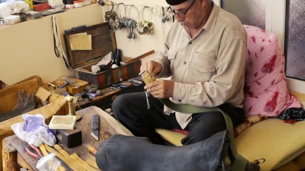 Saddler. Saddle manufacture. Leather goods craftsman at work in his workshop. Artisan Leather. Saddle crafting. Old vintage art. Traditional sewing leather to the point of saddle. Azerbaijan old art. — Stock Video