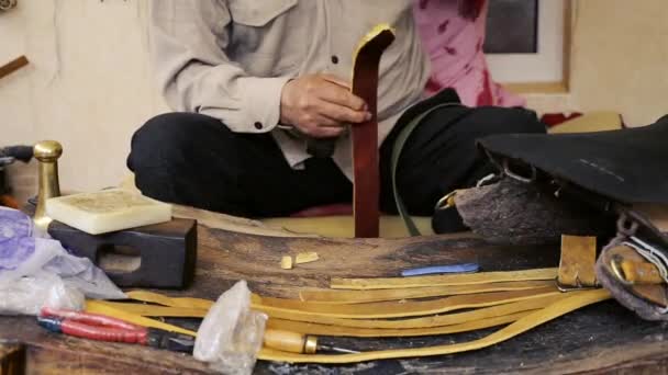 Z'n. Zadel vervaardiging. Lederen goederen ambachtsman op het werk in zijn werkplaats. Artisan leder. Zadel crafting. Oude vintage art. De leer van het traditionele naaien tot het punt van het zadel. Azerbeidzjan oude kunst. — Stockvideo