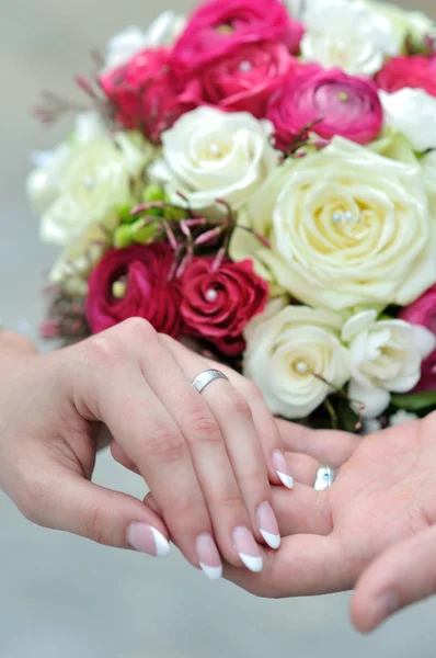 Les mains des jeunes couples mariés et le bouquet de mariage — Photo