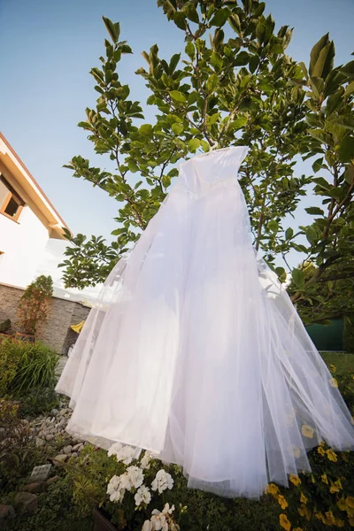 Weißes Hochzeitskleid hängt im Garten — Stockfoto