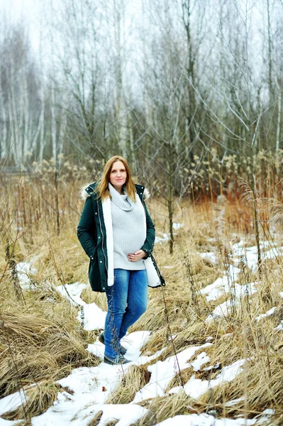 Junge glückliche schwangere Frau im verschneiten Wald — Stockfoto