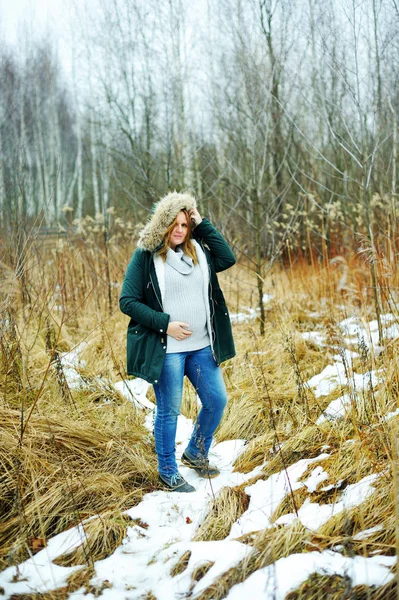 Junge glückliche schwangere Frau im verschneiten Wald — Stockfoto