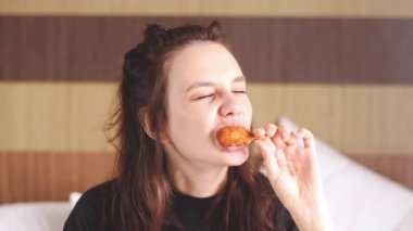 Genç ve güzel bir kadın tavuk kanadı yiyor.