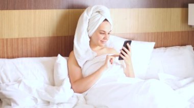 Duştan sonra güzel bir kız yatakta oturur, güzel bir mesaj alır ve sevinir.