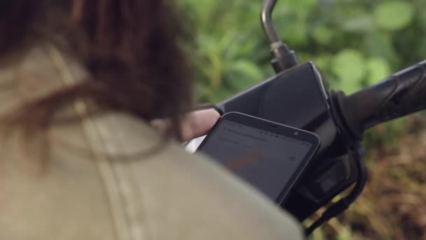 Fille voyageur texto un message sur le téléphone s'arrêtant sur un vélo au bord de la route au lever du soleil 