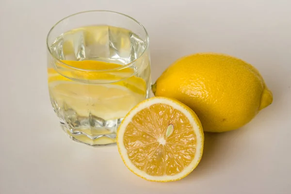 Лимоны и стакан воды с ломтиками лимона . — стоковое фото