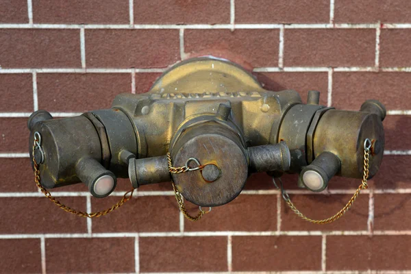 Hydrant mit Wasserschläuchen und Feuerlöschgeräten auf Ziegelstein — Stockfoto