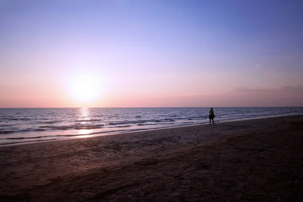 Woman walking on beach under sunset light — Stock Photo, Image