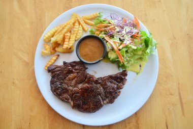 Ahşap arka plan üzerinde antrikot biftek salatası ve patates kızartması ile