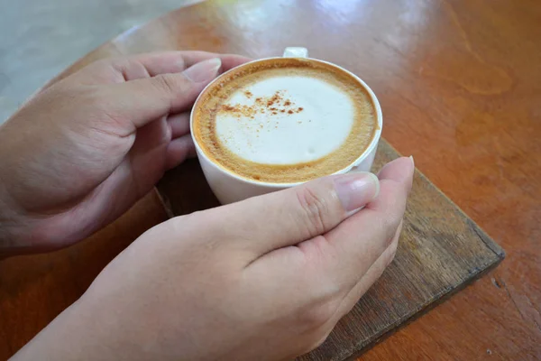 Kobiece ręki trzymającej filiżankę gorącej kawy na stół z drewna, widok z góry — Zdjęcie stockowe