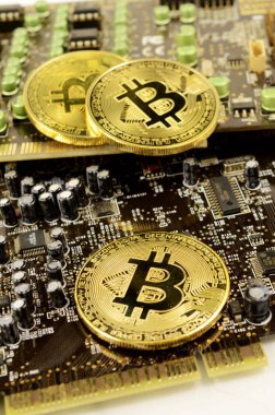 Dijital kripto para biriminin detaylarını göstermek için bir devre kartının üzerinde duran Bitcoin 'lerin yakın görüntüsü.