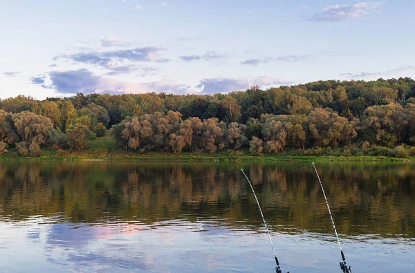 Quiet hunting fishing on the river two fishing rods on the shore of the forest earlier morning