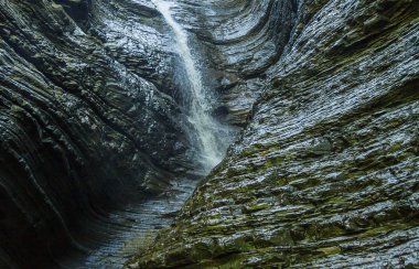 duvar güneş ışığı mağaranın arka planda bir şelale. Yıpranmış ıslak duvar, taş doku arka plan üzerine düşen su