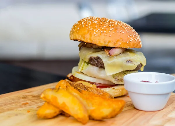 Duże soczyste burger z wołowiny zachwycający patlet z smażone ziemniaki w plasterkach, szybki lunch kawiarni ulicy — Zdjęcie stockowe