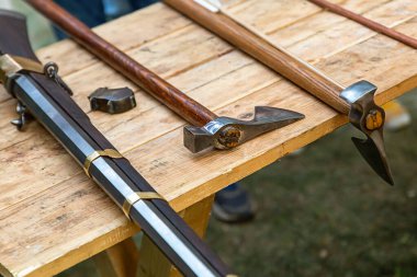 Masanın üzerinde bir çift uzun saplı balta ve siyah silah çeşitleri vardı.