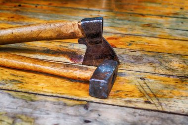 Alet seti balta ve çekiç demiri, sıcak renklerde bir bina ahşap tahtalar üzerinde uzanır.