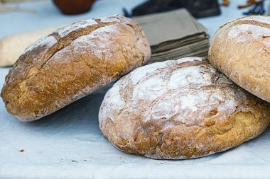 Beyaz bir masa örtüsünün üzerine serpiştirilmiş un serpiştirilmiş taze kır ekmeği yığını.