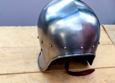 Demir ve parlak miğfer hafiftir. Savaşçının koruması masanın üzerindedir.