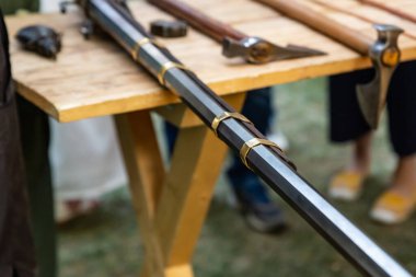 Silah demiri siyah namlu, arka planda bulanık bir savaş baltasında altın çizgiler olan uzun bir yakın plan.