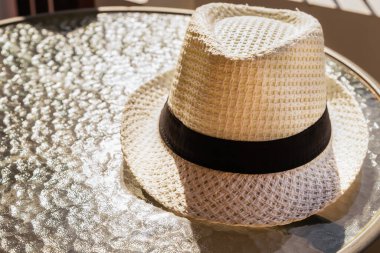 Kavurucu şapkaya karşı beyaz koruma bir sokak kafesinin cam masasında yatıyor.