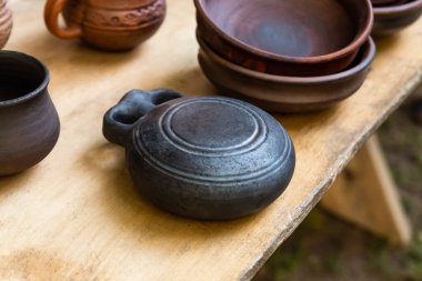 Toprak saklama kabı ve tabağı ahşap bir masanın üzerinde duruyor.