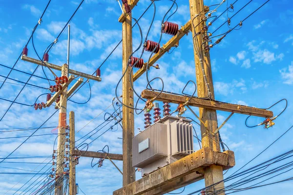 kullanıcılar için elektrik tedarik sistemi, yüksek voltajlı güç transformatörleri ahşap direklere monte edilmiş mavi gökyüzü arka planında