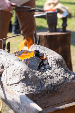 Bir demircinin çalışmalarının ortasında yanan kömürle kaplı taş boynuz.