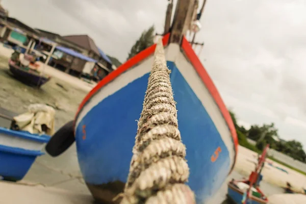 渔船用一根旧电缆把深蓝色和红色的木船系在码头上 — 图库照片