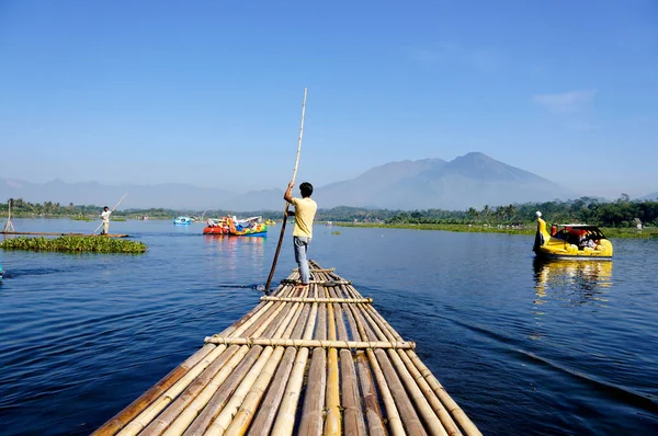 Man rowing a raft on the river in Indonesia.